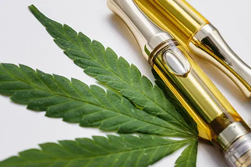 Vape Pens mit Kartusche, daneben ein Cannabisblatt